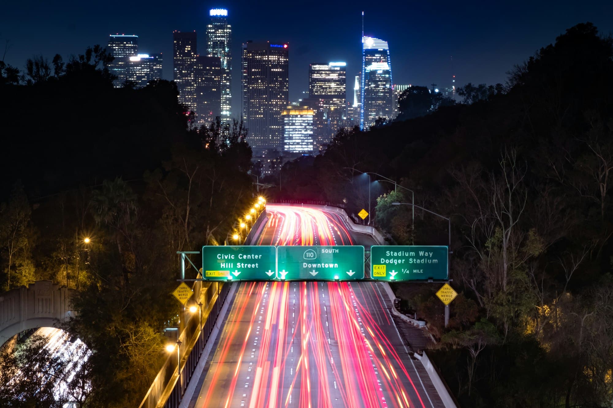 Night motorway with light trails heading towards a city skyline