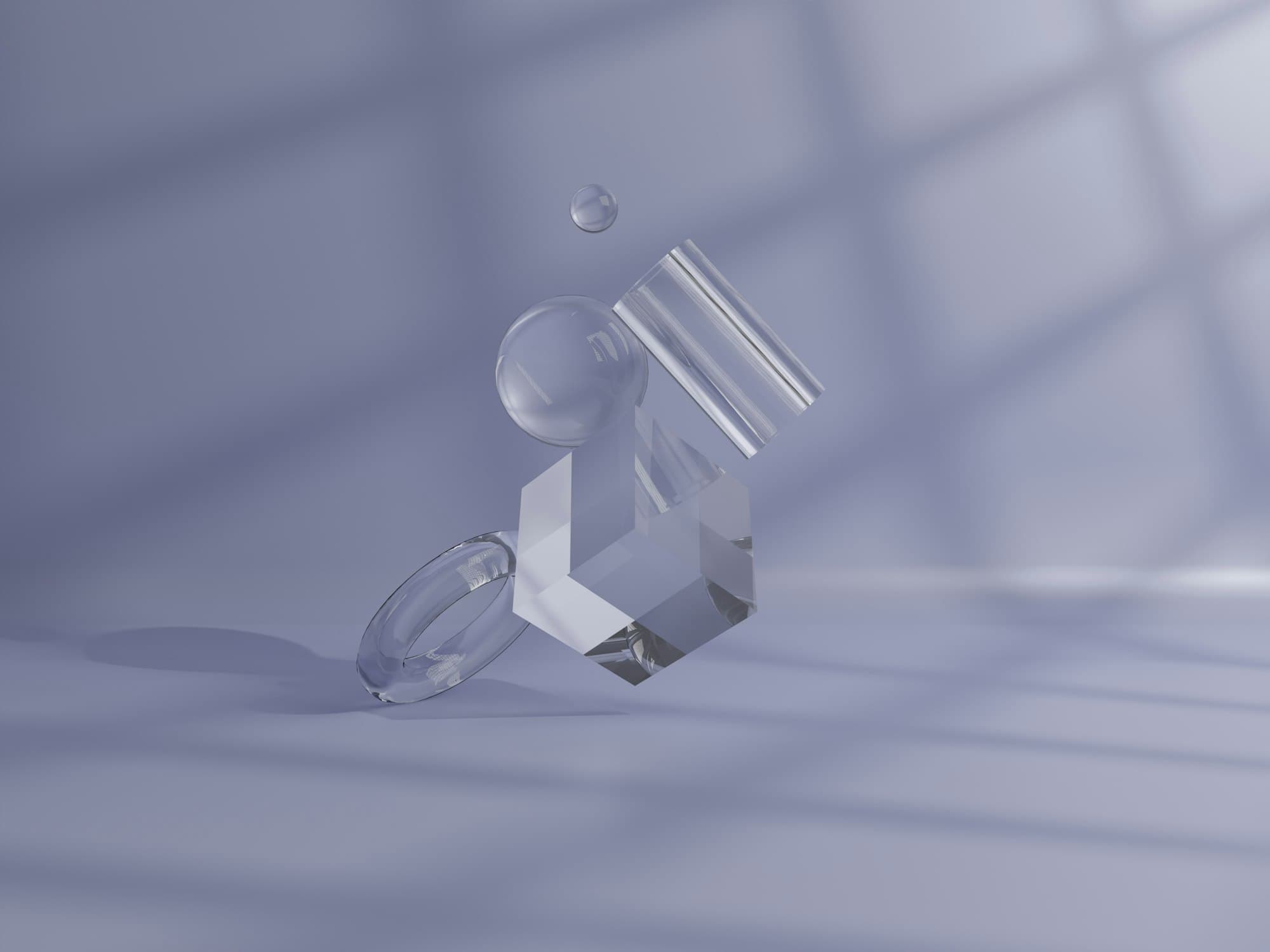 Clear geometric shapes, including a cube, ring, sphere and cylinder, on a pale background