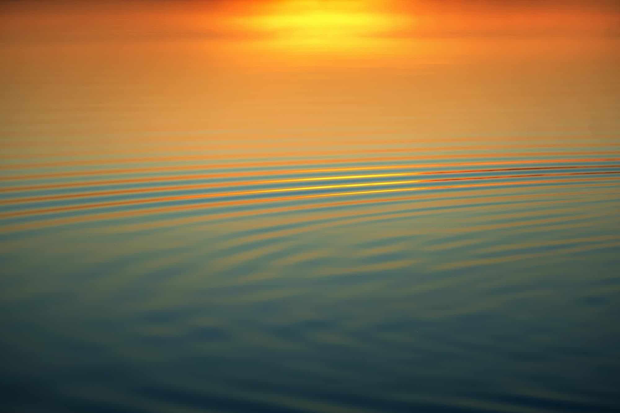 Calm water at sunset with long horizontal ripples